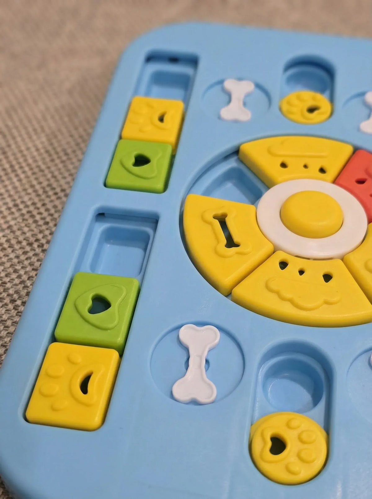 Close up of the sliders, bone covers and rotating wheel on the Level 2 dog puzzle toy