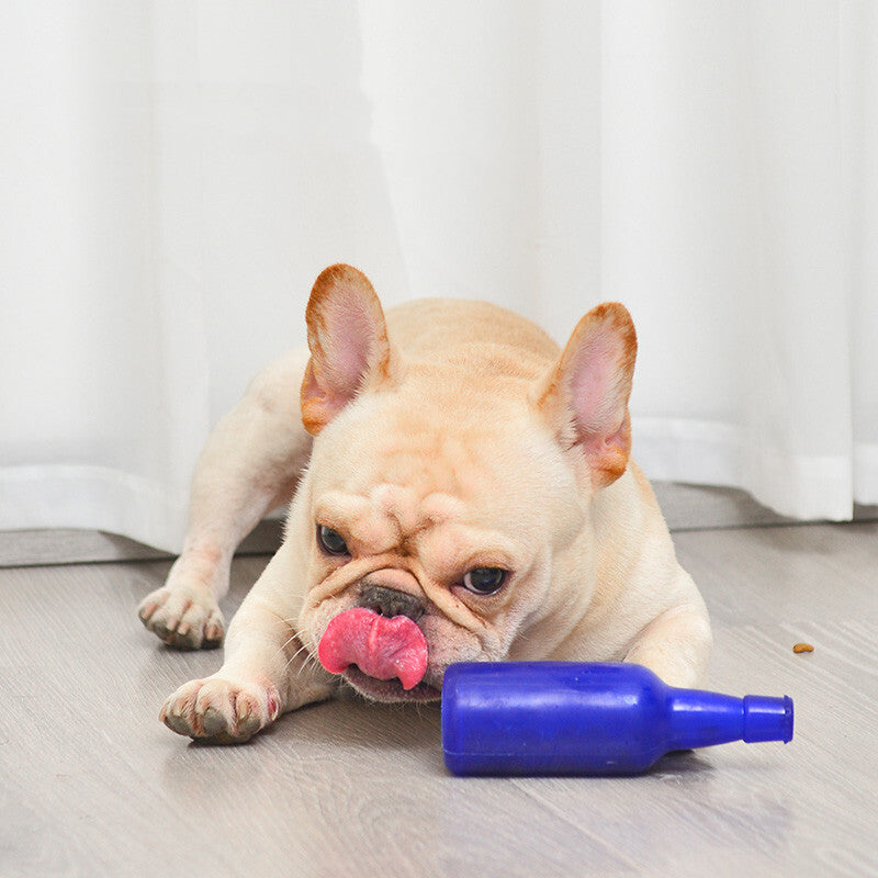 French bulldog puppy lying beside a blue bottle-shaped Puppy Treat Toy