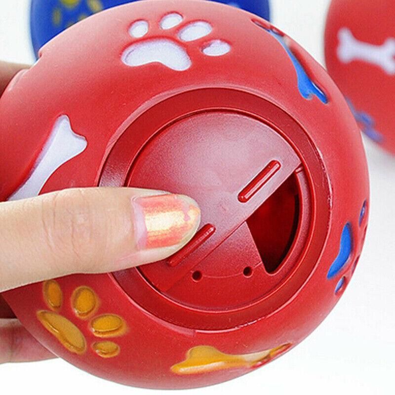 Finger turning the adjustable treat opening on the red Treat Tumbler Ball