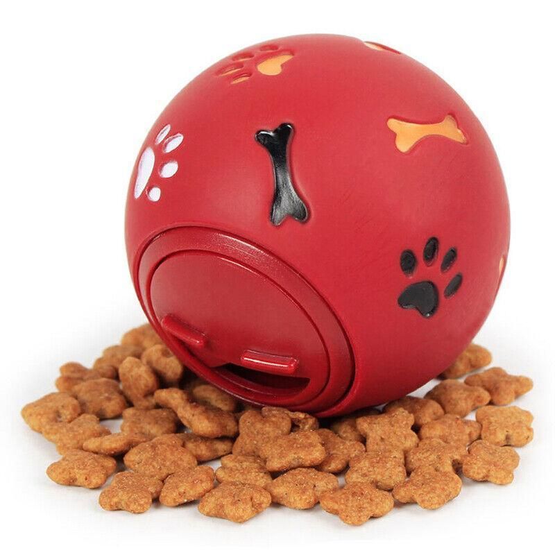 Red Treat Tumbler Ball for dogs sitting on a pile of bone-shaped biscuits